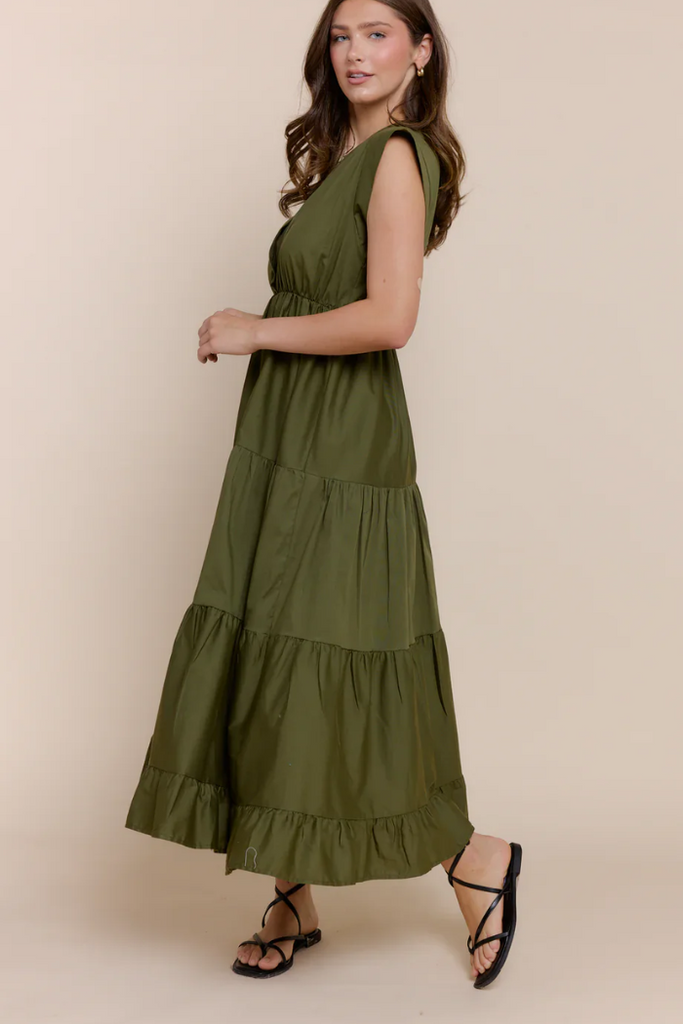 Woman wearing an olive green dress with a plain background