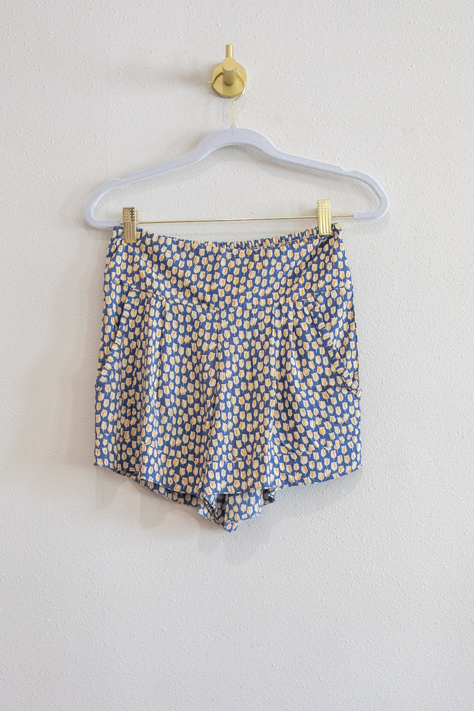 Floral-patterned shorts hanging on a white hanger against a light background