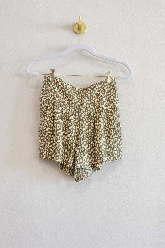 Floral-patterned shorts on a hanger against a plain background