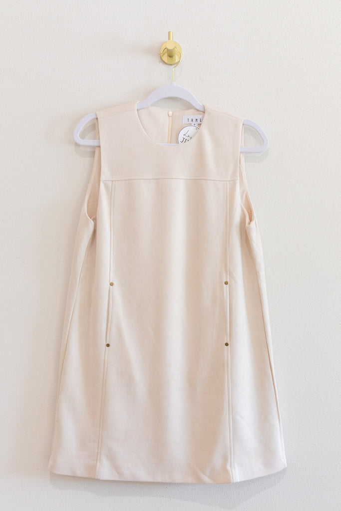 Beige sleeveless dress on a hanger against a white wall